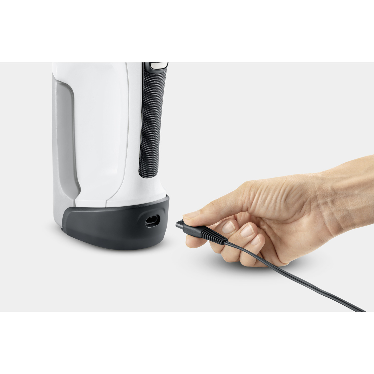 A hand plugging a cable into a white and grey device, likely an electronic appliance.