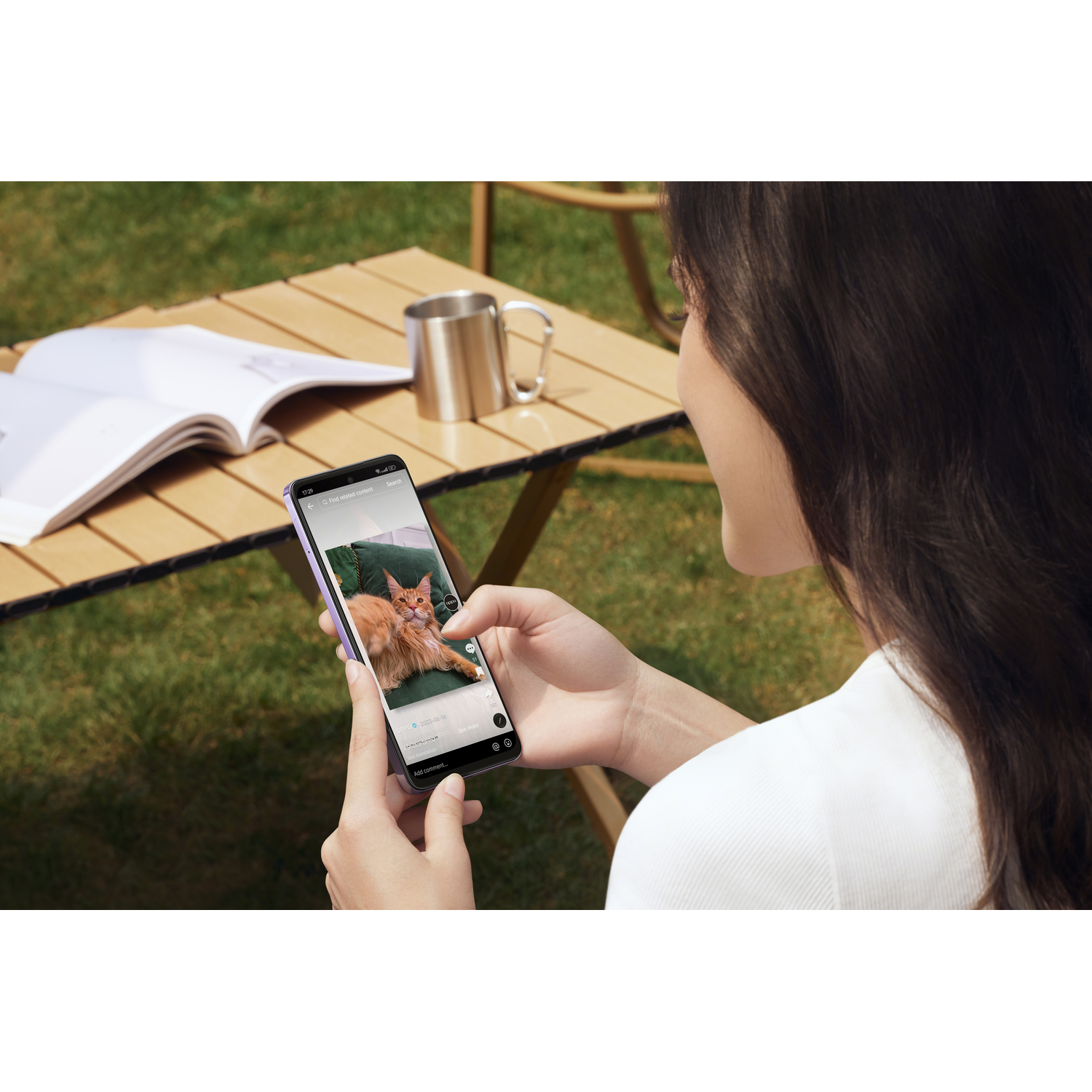 Vrouw die een telefoon vasthoudt, met een foto van twee katten op een tafel.
