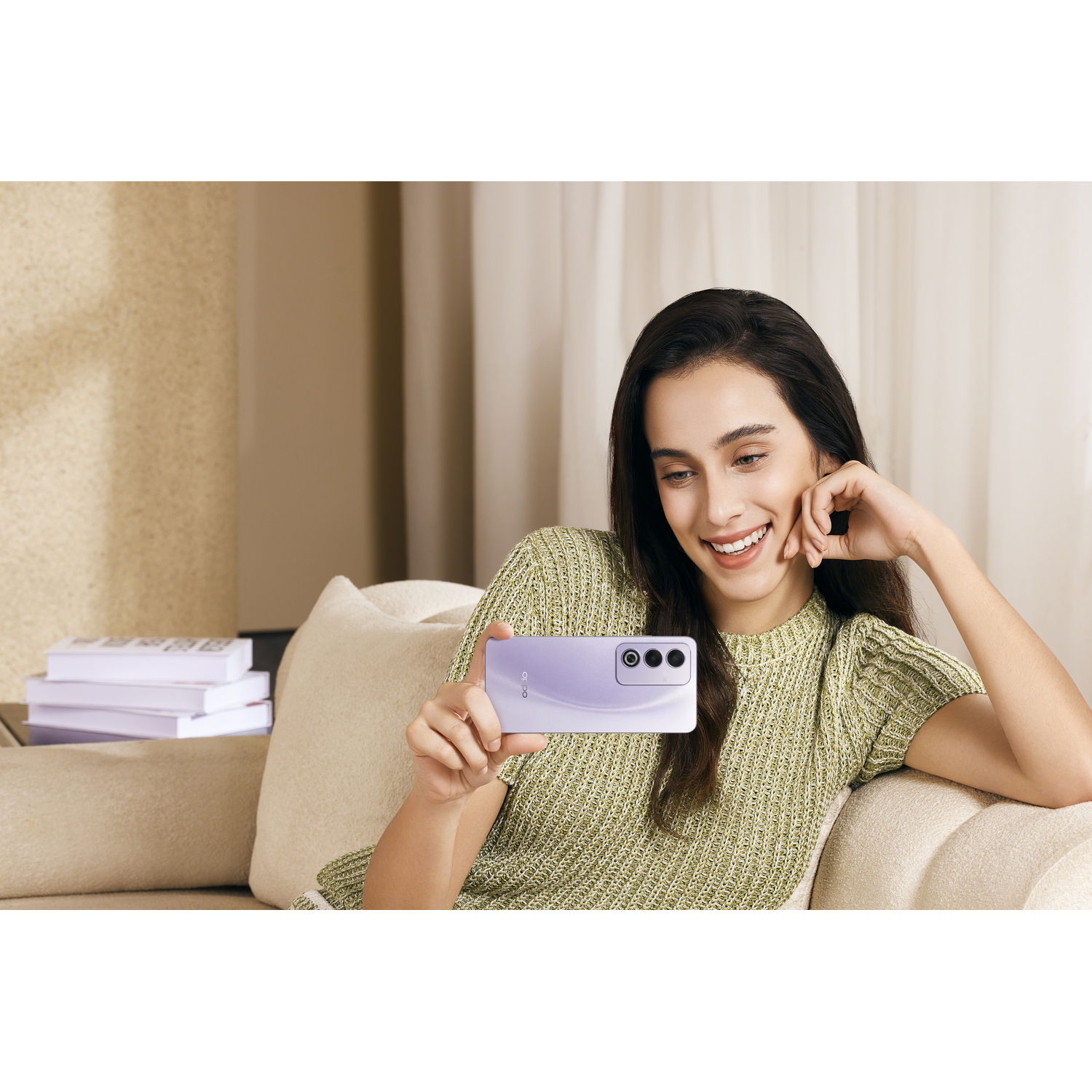 Vrouw die een selfie maakt met een paarse telefoon, glimlachend op een bank.