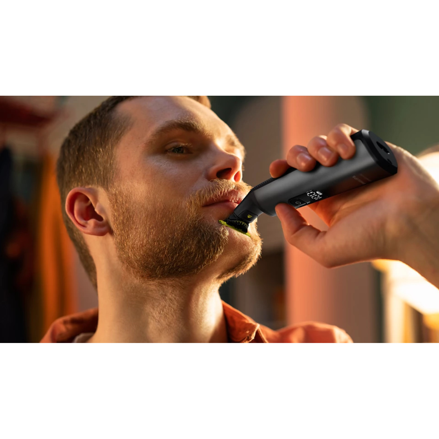 A man shaving his beard with a black electric shaver, close up shot.