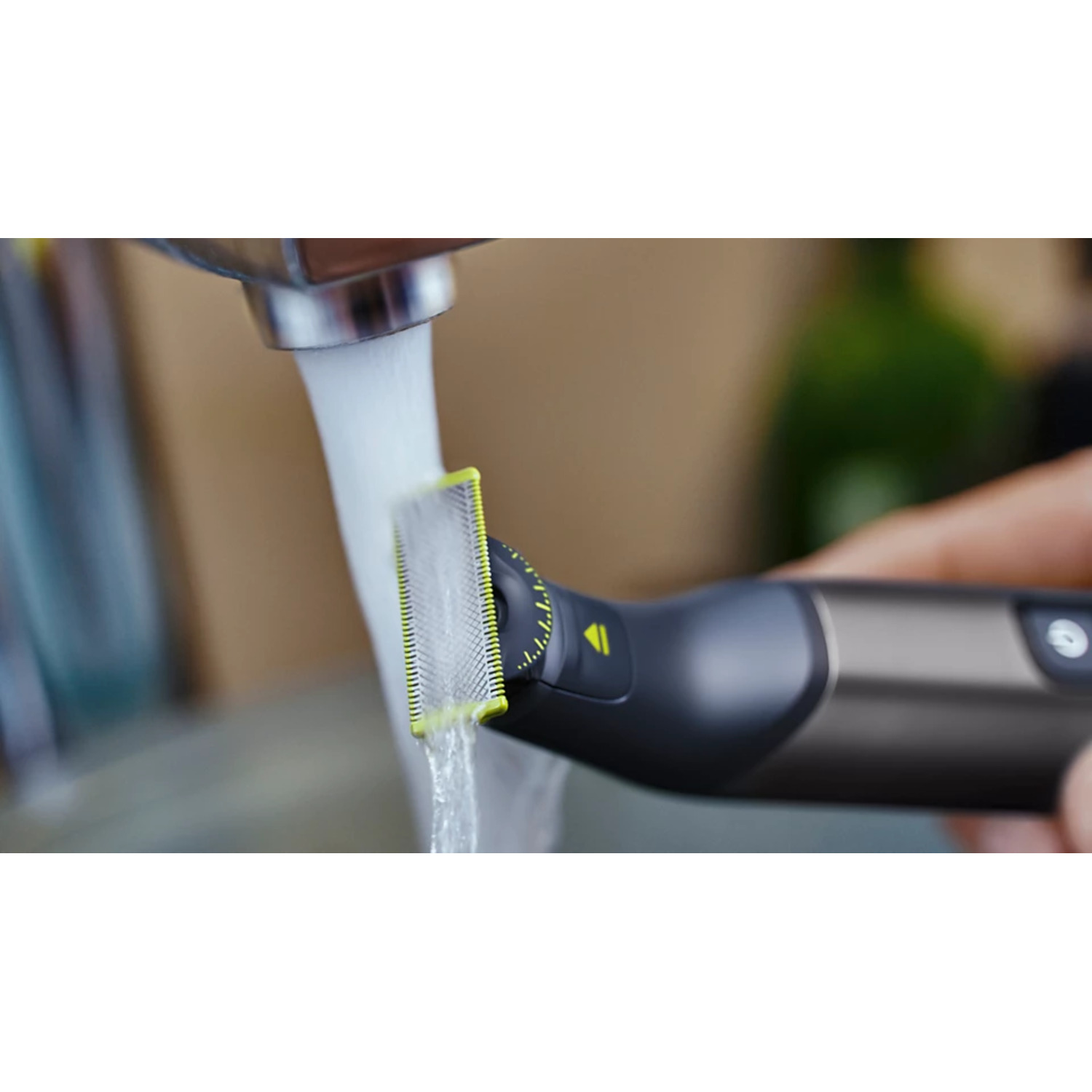 Water running over a black and yellow electric shaver, held by a hand.
