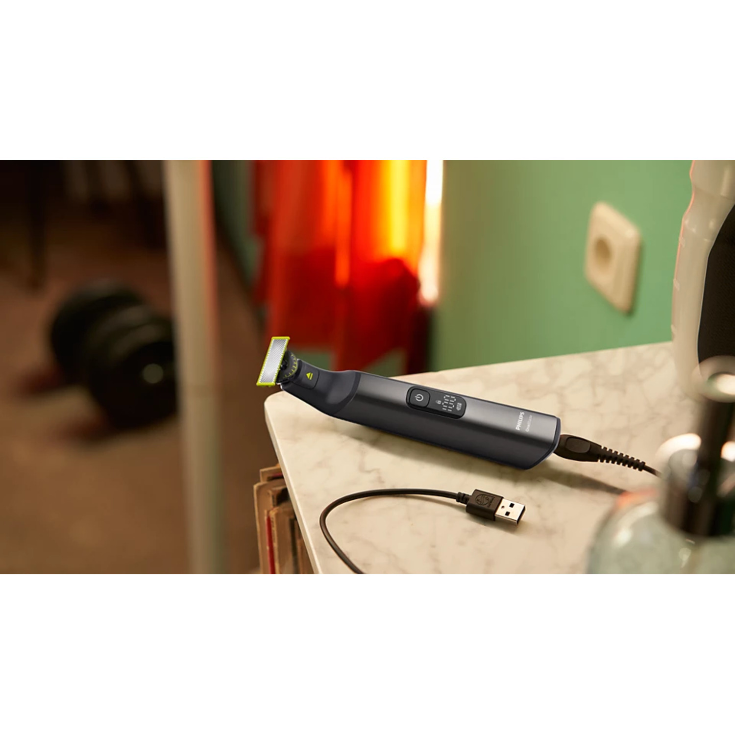 A black and gray beard trimmer with a USB cable on a white countertop.