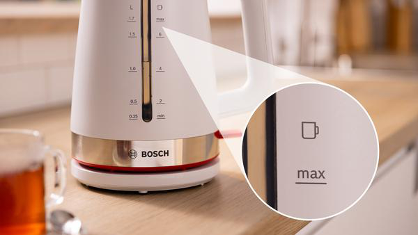 Ein weißer und goldfarbener Wasserkocher. Eine Nahaufnahme zeigt die max. Füllstandsanzeige.