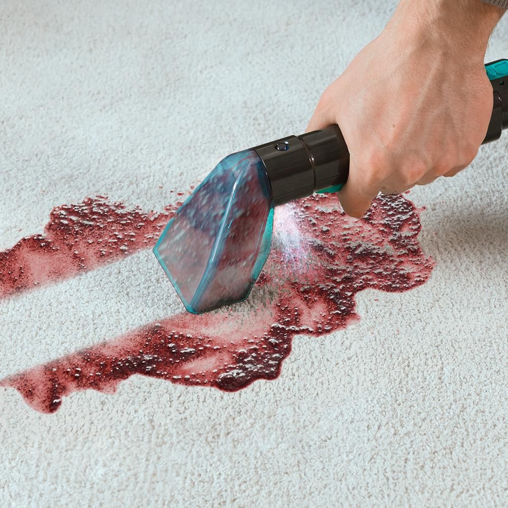 Persona usando una herramienta de limpieza en una alfombra manchada. Herramienta turquesa.