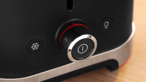 Nahaufnahme eines schwarzen und roten Toaster-Bedienfelds. Es hat einen Drehregler und Knöpfe.