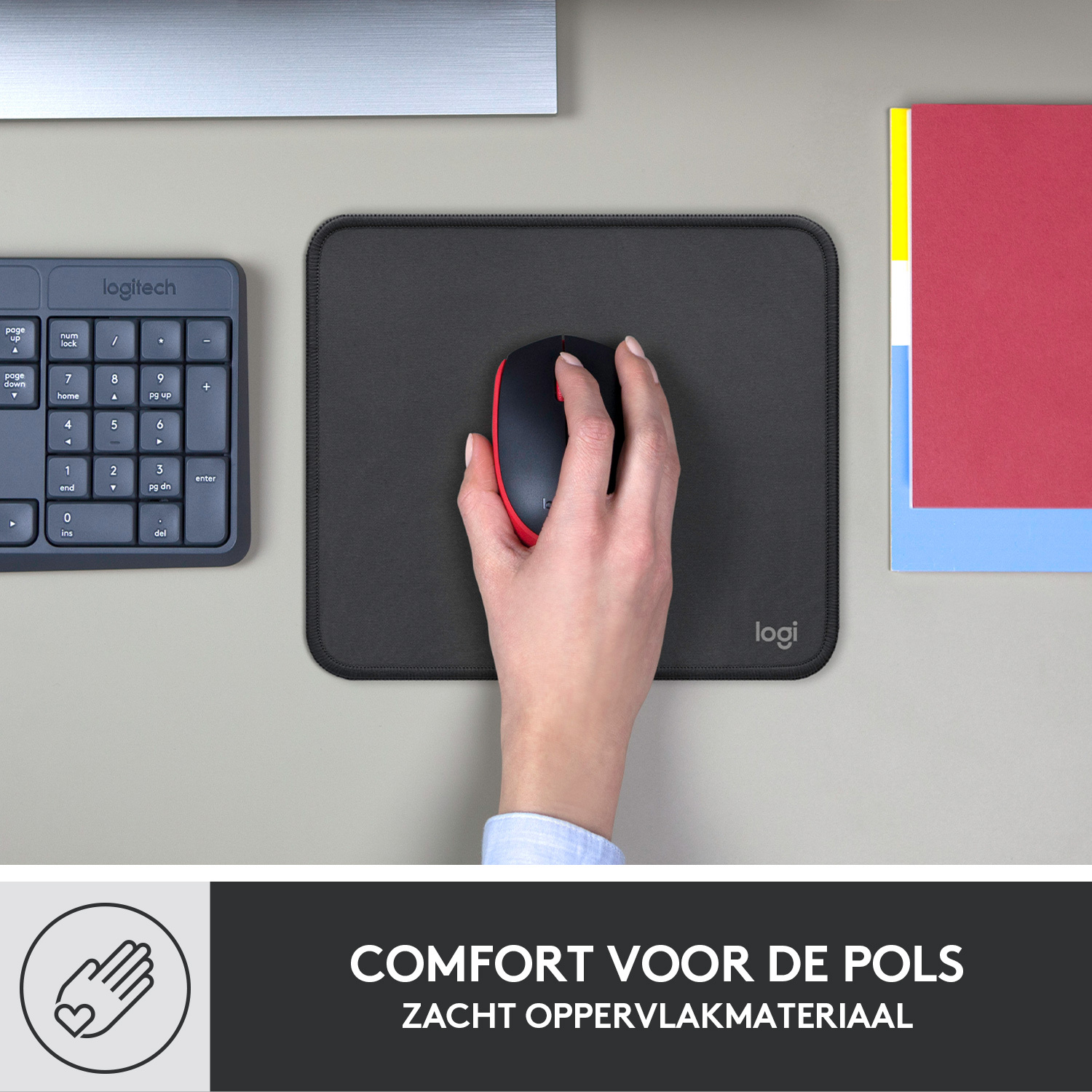 Hand met een muis op een zwart muismatje met een toetsenbord en notities aan de zijkanten.
