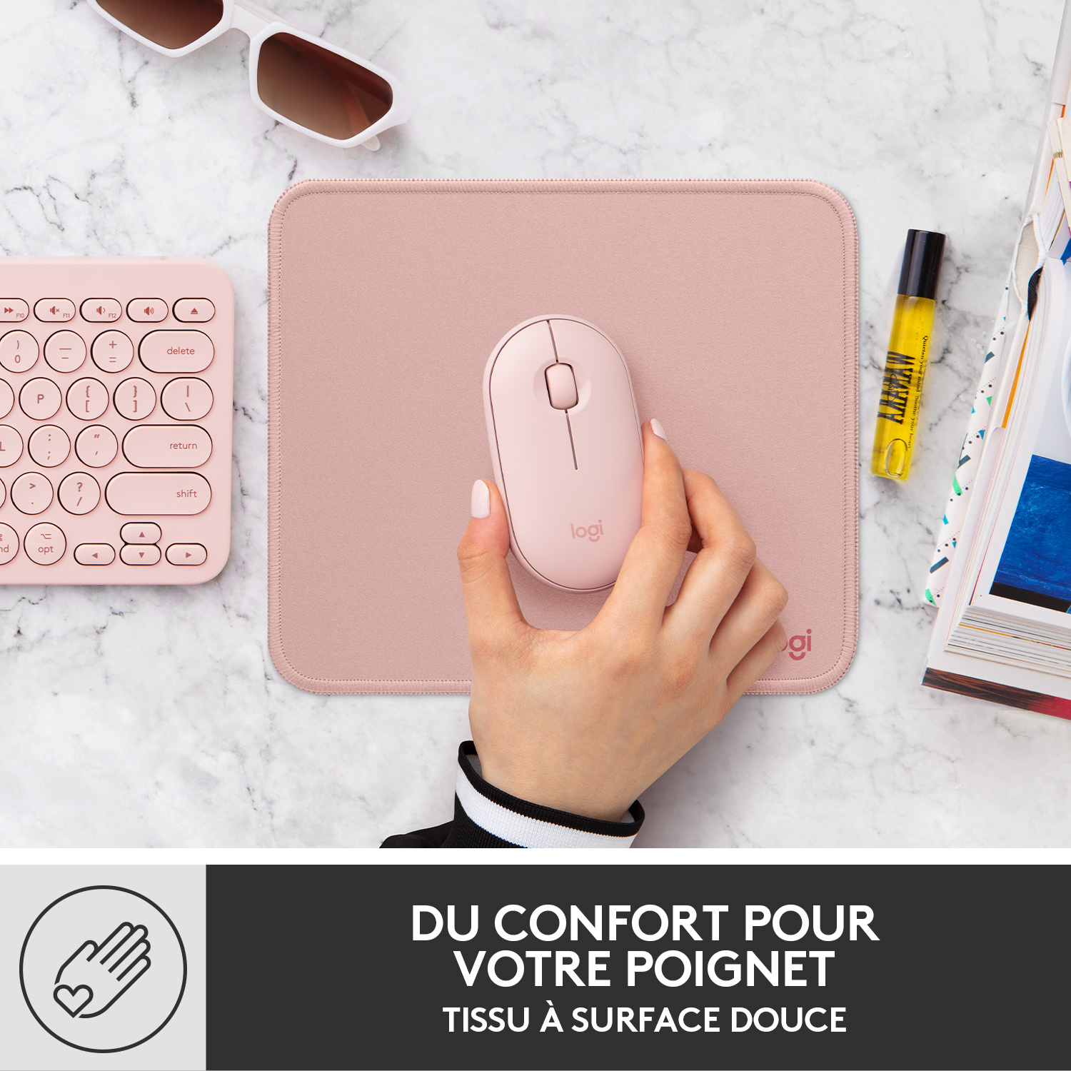 Main tenant une souris rose sur un tapis de souris rose.