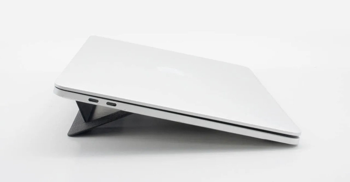 Srebrny laptop na czarnym stojaku pod kątem. Laptop jest zamknięty.