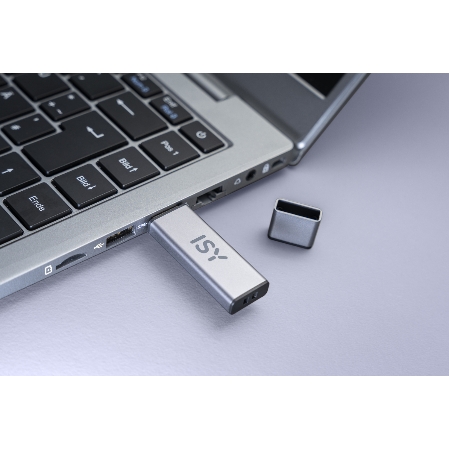 Silver USB drive plugged into a laptop. The drive has 'ISY' printed on it, and a cap is next to it.