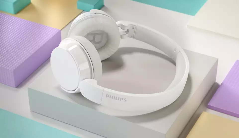 Renkli bloklarla beyaz bir yüzeyde beyaz Philips kulaklıklar. Kulaklıkların Philips logosu var.
