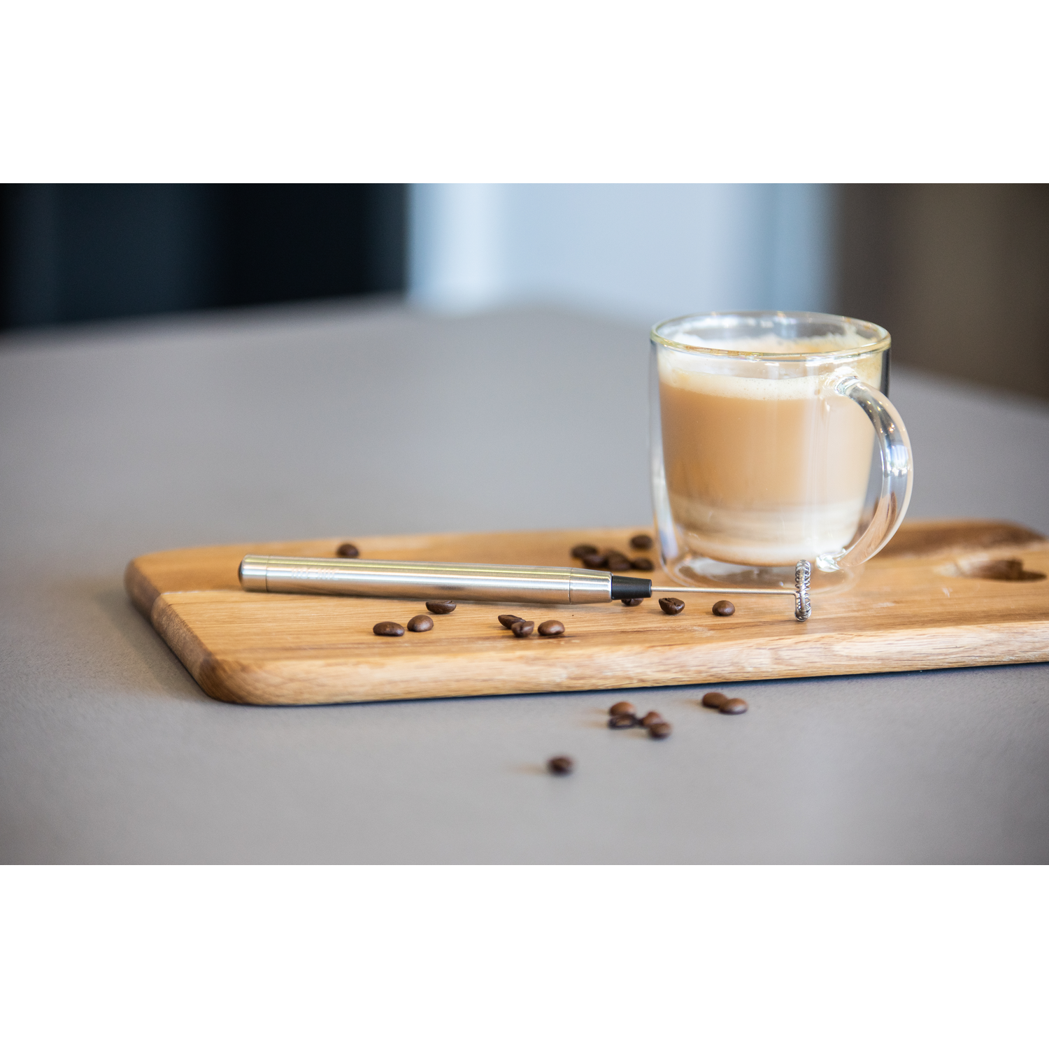 Een houten plank met koffie, een melkopschuimer en koffiebonen.