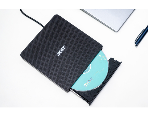 Schwarzes Acer DVD-R-Laufwerk mit einer Disc im Inneren, auf einem weißen Schreibtisch platziert.