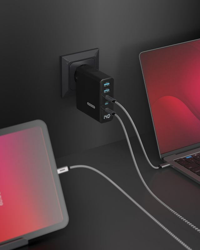 Adattatore di alimentazione nero collegato a una parete con un tablet e un laptop collegati.