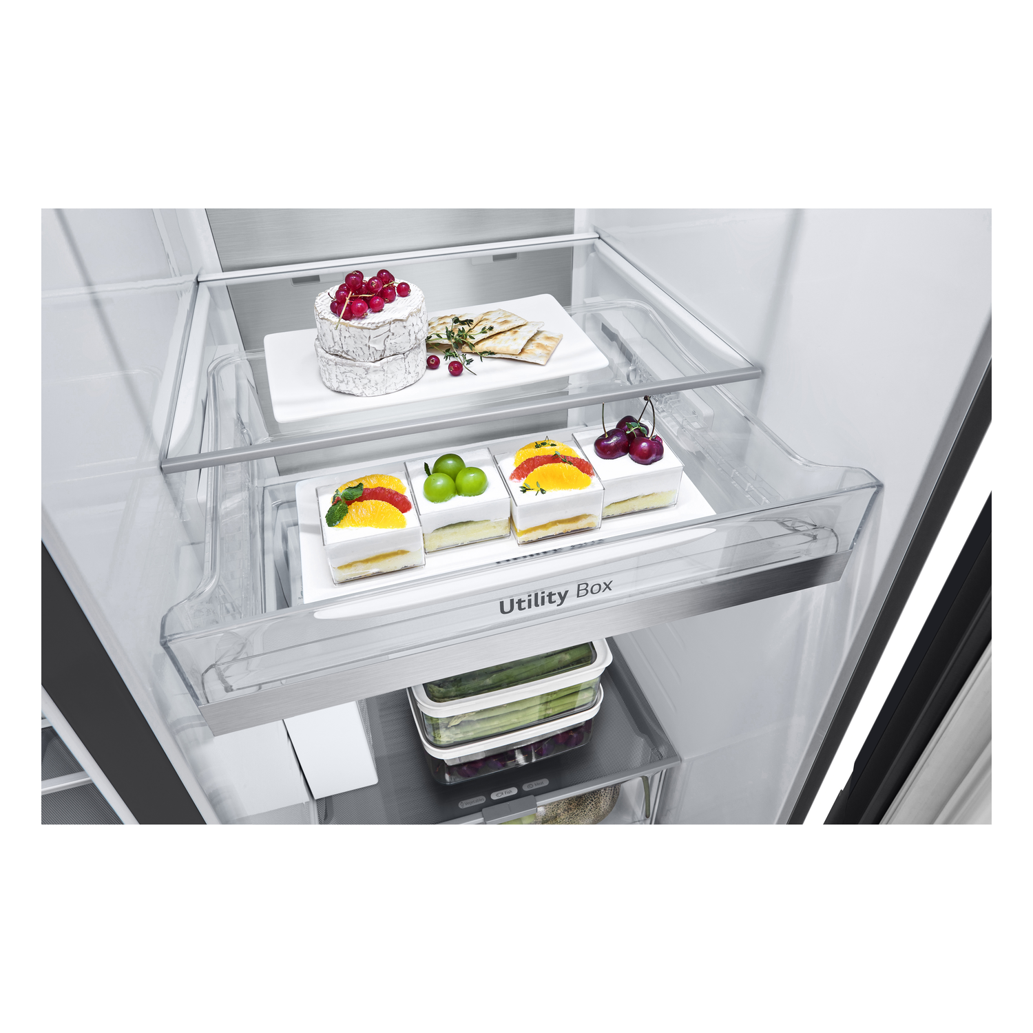 Inside a refrigerator, showing drawers with food items. A cake and fruits are visible.
