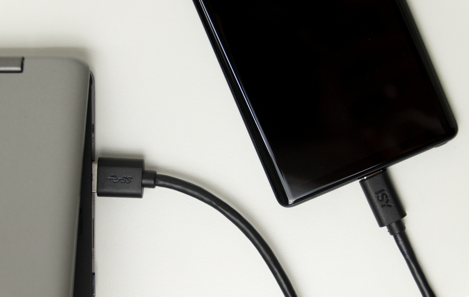 Una computadora portátil conectada a un teléfono con un cable USB-C negro. El teléfono es negro.