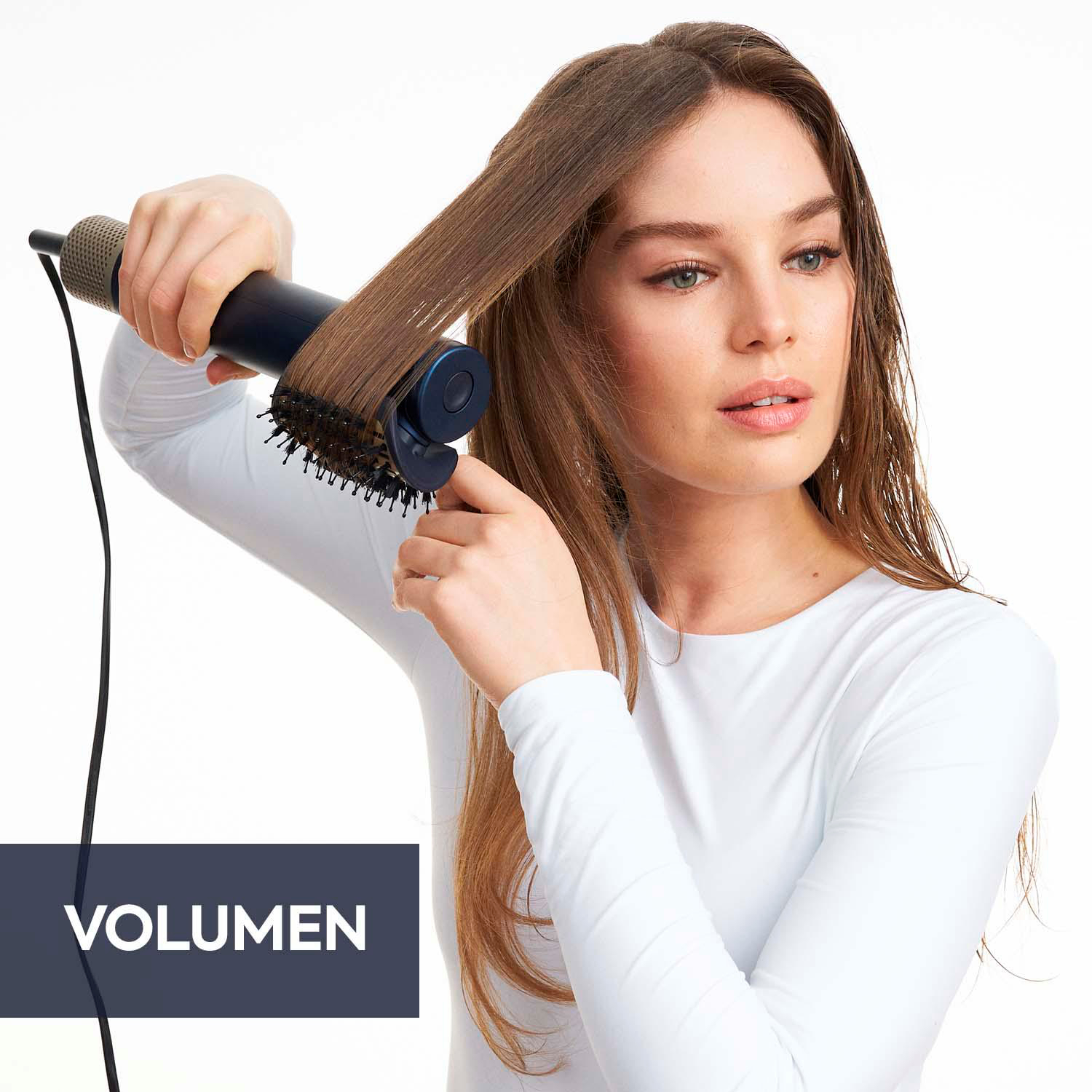 Frau, die ihr Haar mit einem blau-schwarzen Haartrockner stylt. Weißer Hintergrund. Das Wort VOLUMEN ist sichtbar.