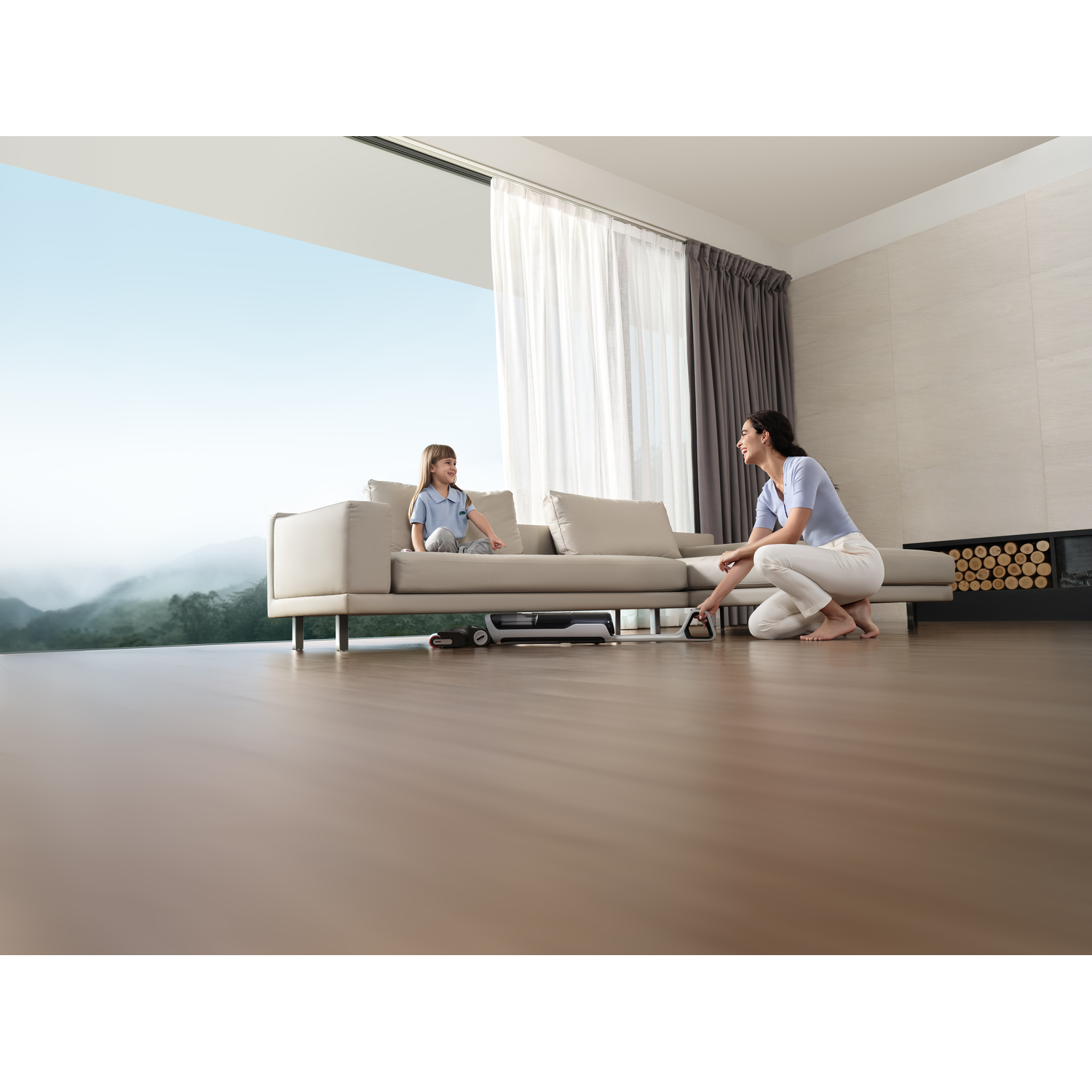 A woman and girl cleaning with a robot vacuum cleaner. Modern living room with a large window.