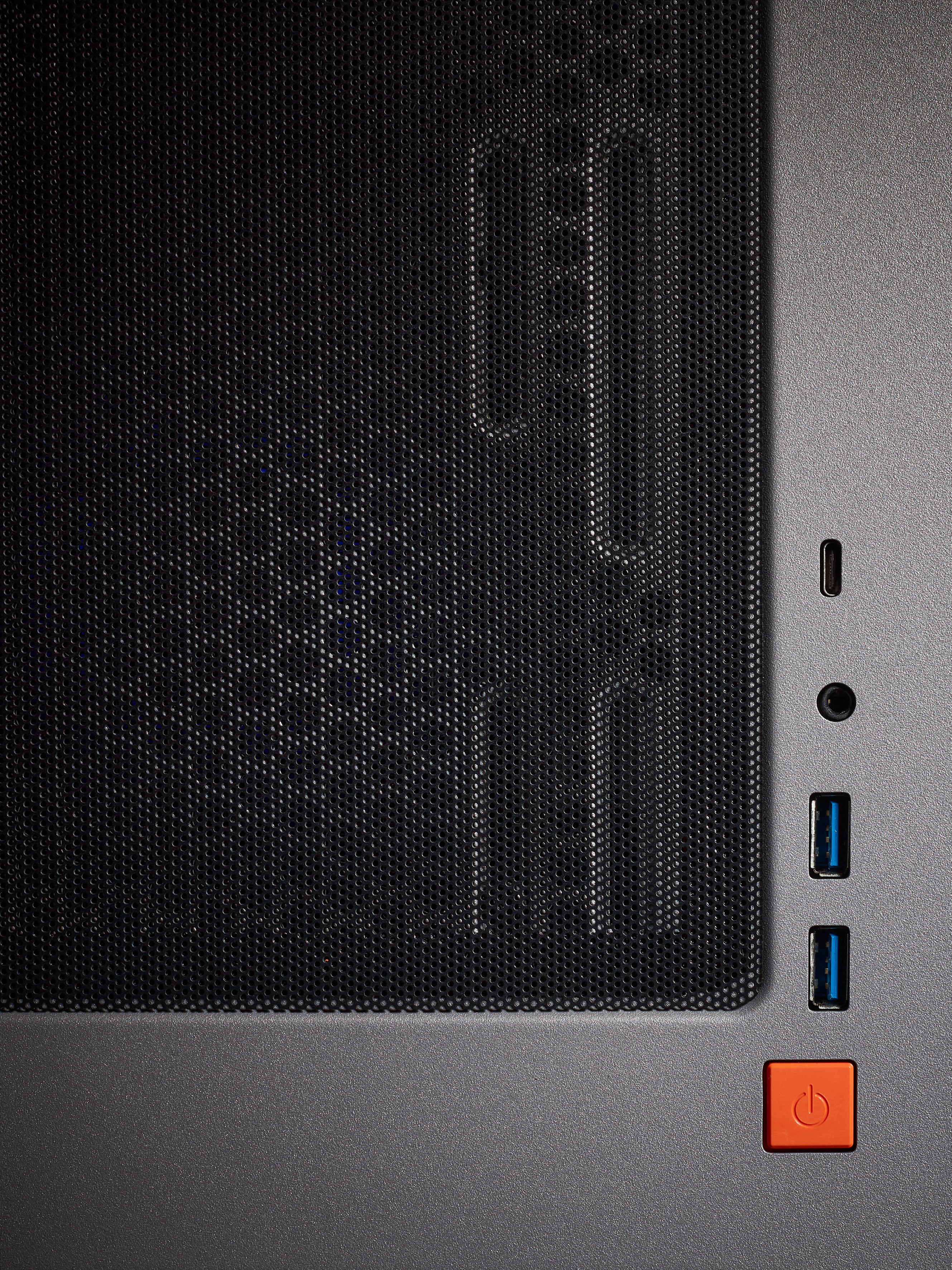 Nahaufnahme eines schwarzen Computergehäuses mit USB-Anschlüssen, Ein-/Aus-Taste, Textur.