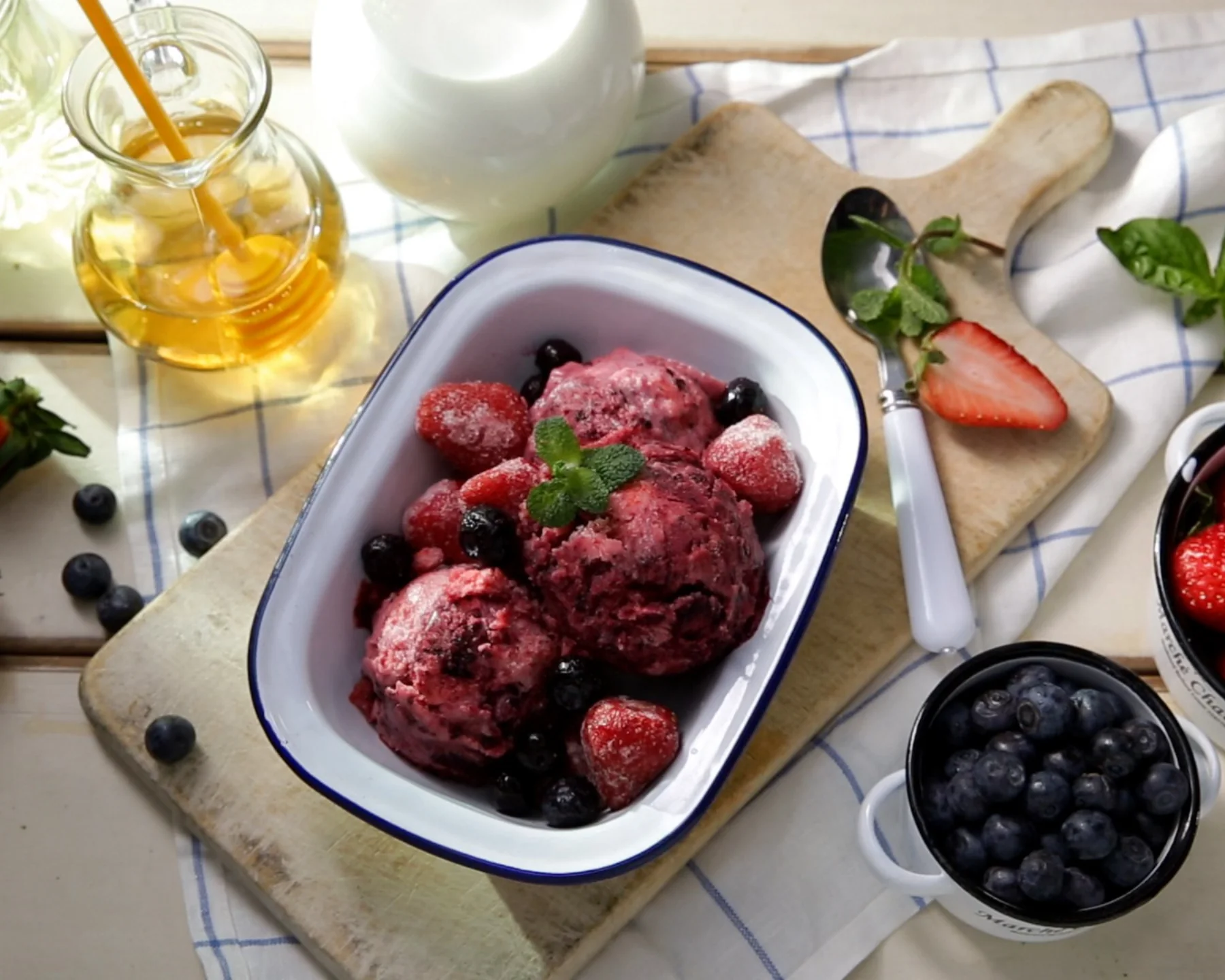 Gelato con frutti di bosco servito in una ciotola bianca con un cucchiaio su un tavolo.