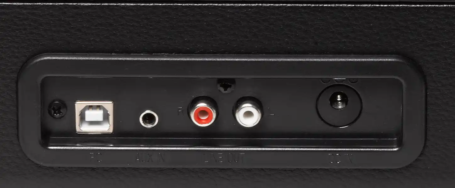 Egy eszköz hátuljának közeli képe, amely USB-, audio- és tápcsatlakozókat mutat fekete felületen.