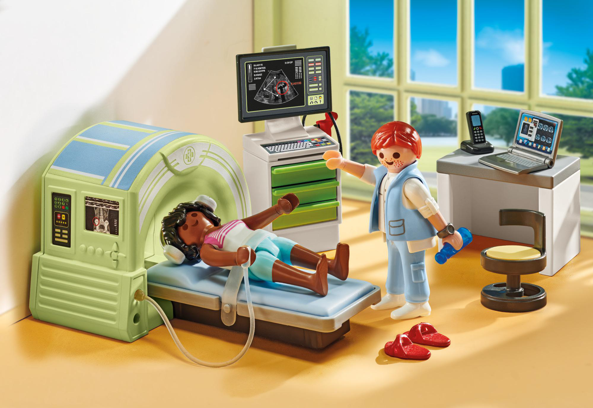 Eine Playmobil-Medizin-Szene. Ein Patient liegt in einem Scanner, ein Arzt zeigt auf einen Bildschirm und einen Laptop.