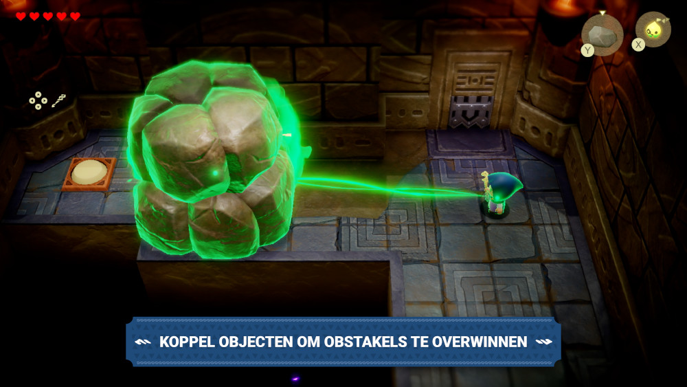 Videogame scène. Een personage staat tegenover een groen oplichtend object. Tekst: 'KOPPEL OBJECTEN OM HINDERNISSEN TE OVERWINNEN'.
