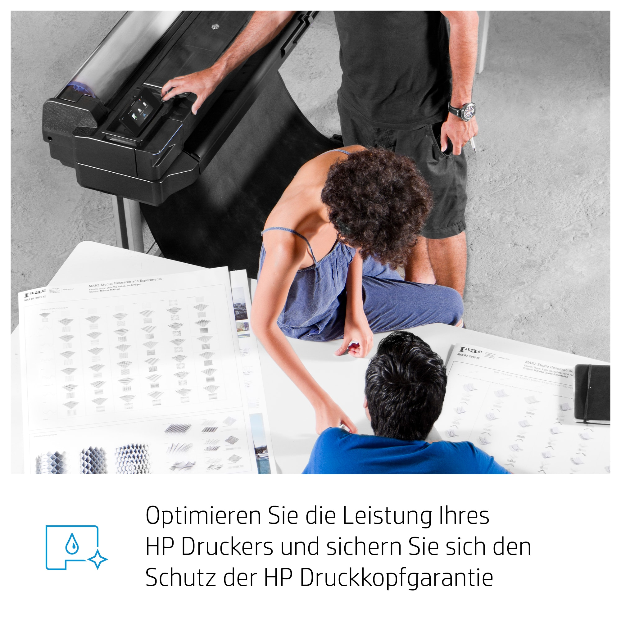 Leute arbeiten mit einem Großdrucker. Einer bedient das Bedienfeld, ein anderer beobachtet.