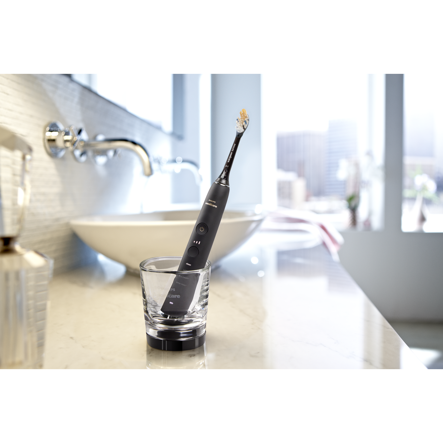 Brosse à dents électrique dans un verre sur un comptoir blanc avec un lavabo en arrière-plan.