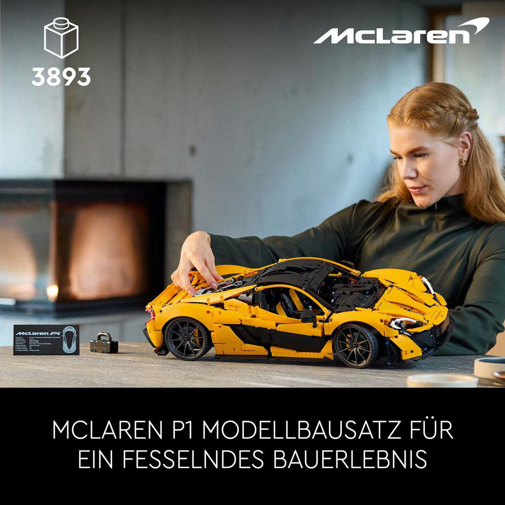 Eine Frau baut ein gelb-schwarzes McLaren P1 Lego-Modell auf einem Holztisch zusammen.
