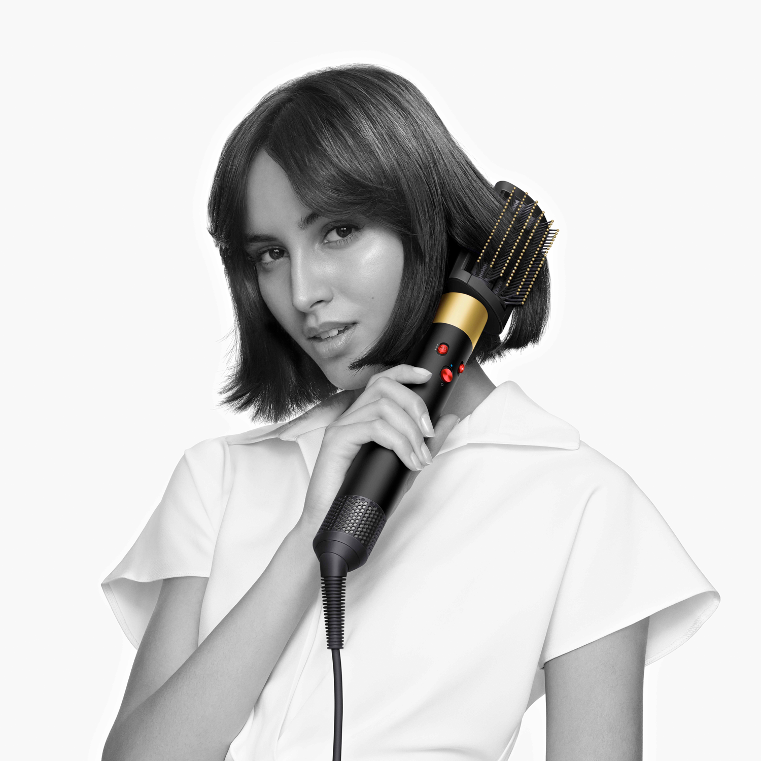 Femme aux cheveux courts utilisant un sèche-cheveux noir, sur fond blanc.