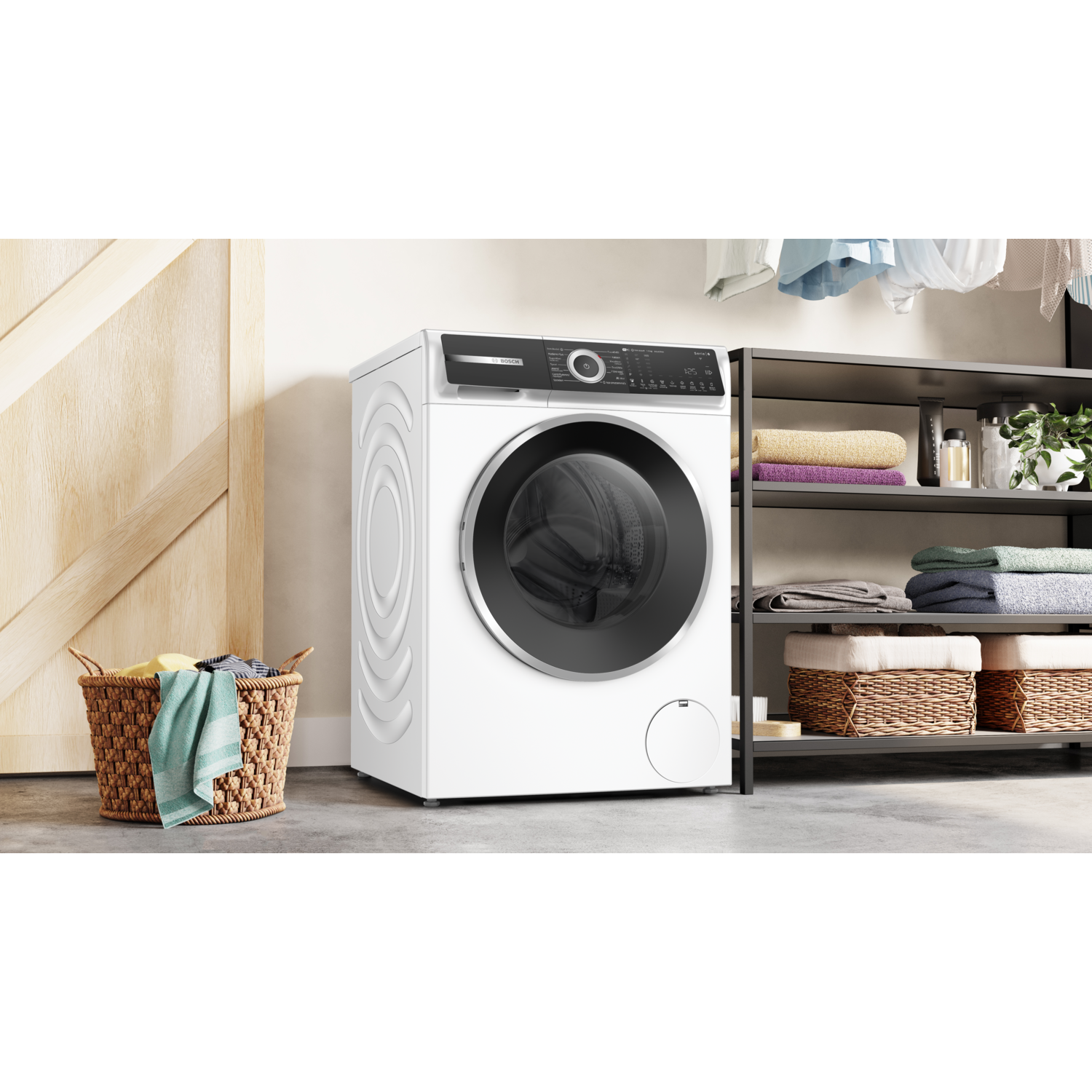 Een witte wasmachine in een wasruimte, kleding en een mand op de voorgrond.
