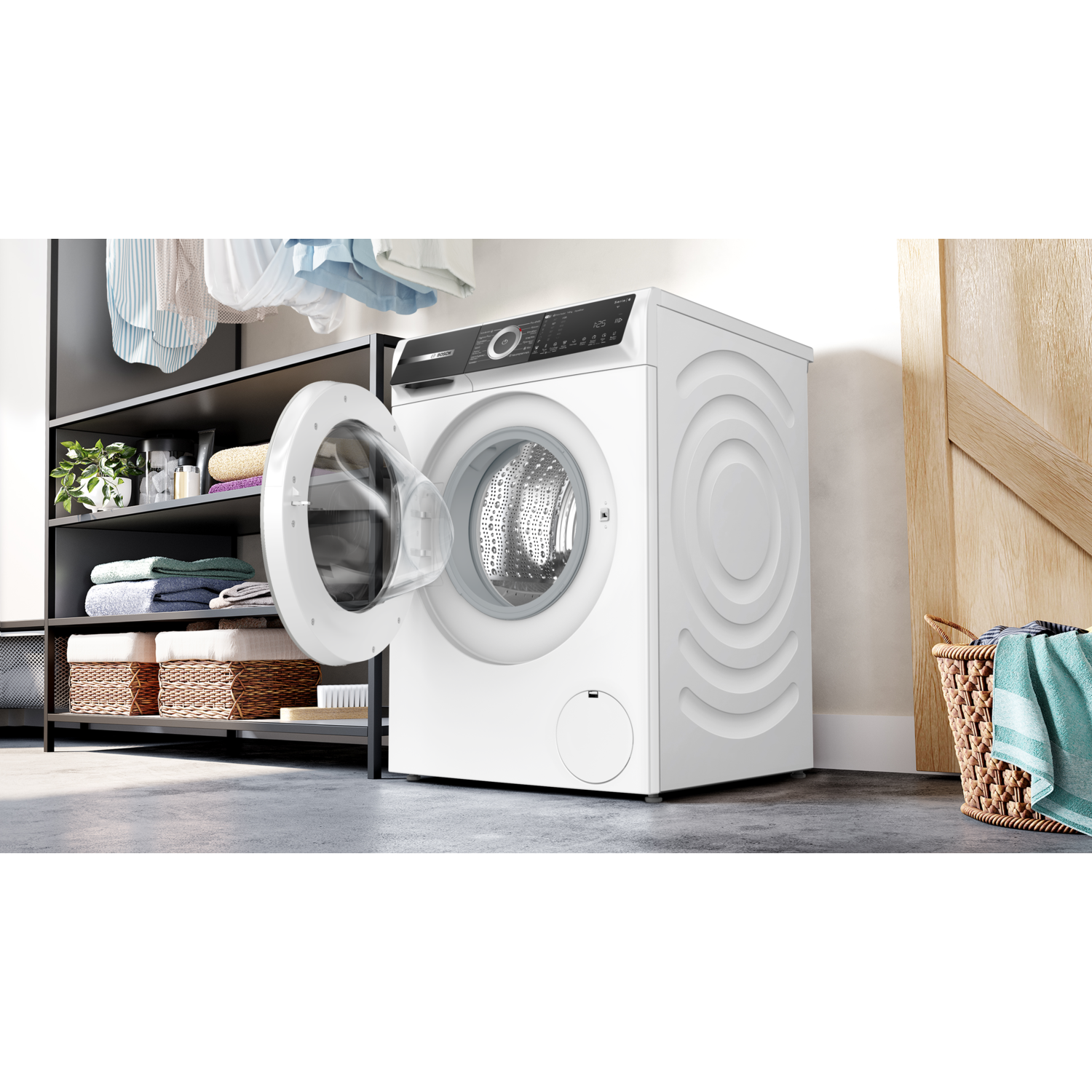 Witte wasmachine met open deur, naast wasmiddelen op planken en een mand.