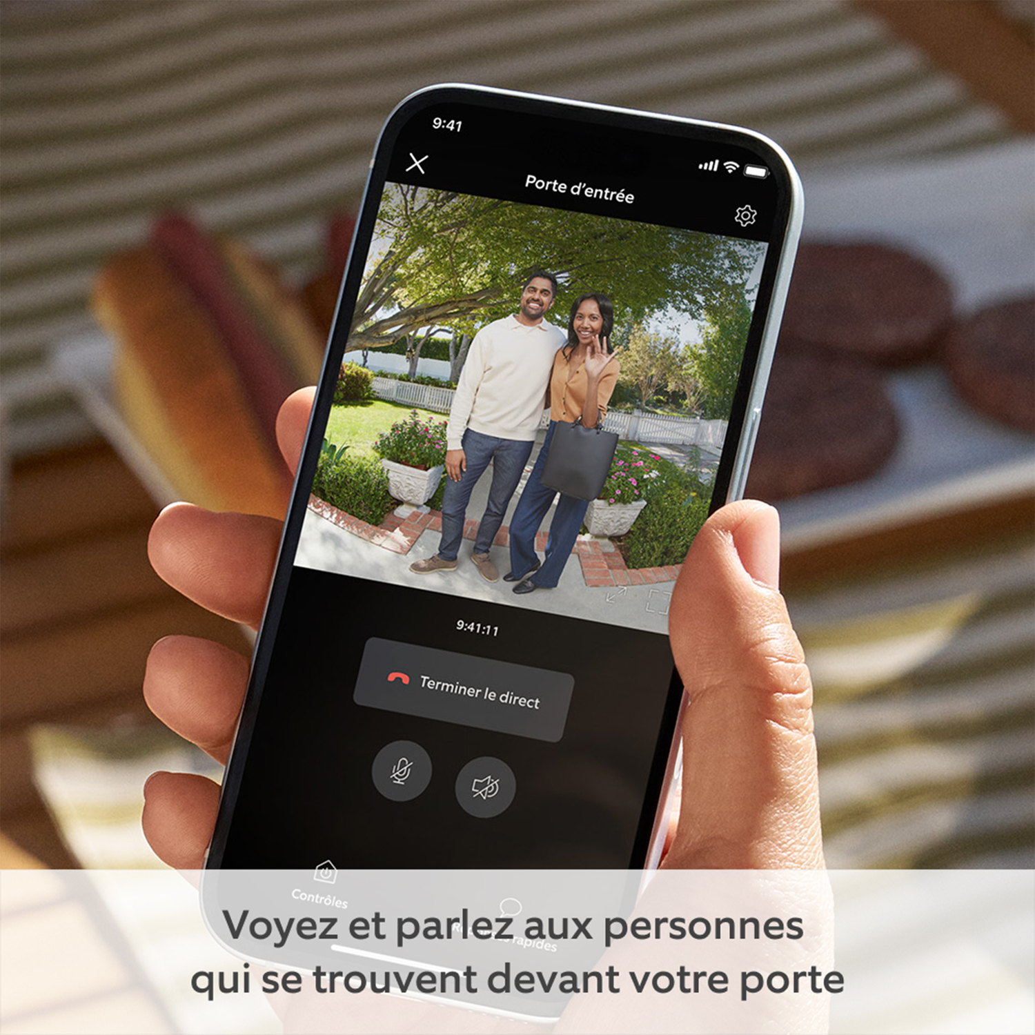 Une personne tient un téléphone montrant un appel vidéo avec des personnes à l'extérieur.