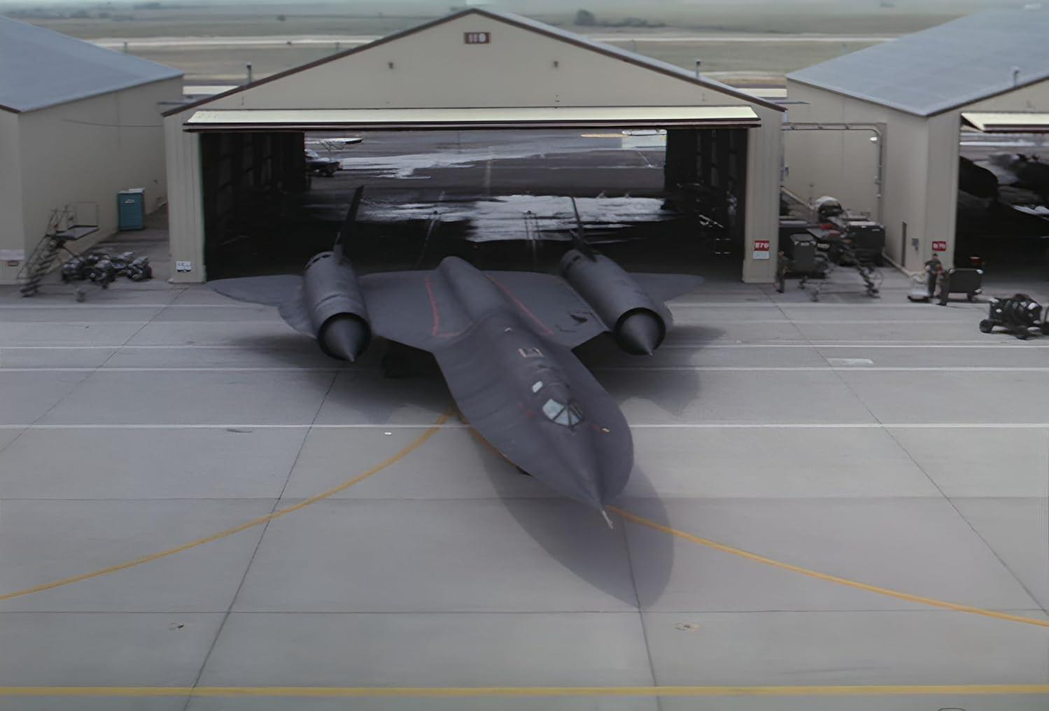 Schwarzes SR-71-Jet auf dem Rollfeld eines Flugplatzes geparkt. Hangars im Hintergrund. Bewölkter Himmel.
