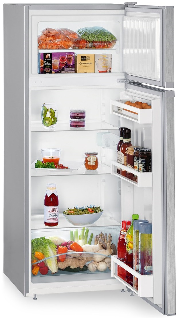 Otwarta lodówka z półkami jedzenia i napojów: warzywa, owoce, słoiki, butelki.