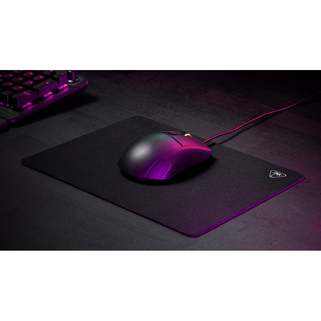Schwarze Gaming-Maus auf schwarzem Mauspad, mit Tastatur im Hintergrund.