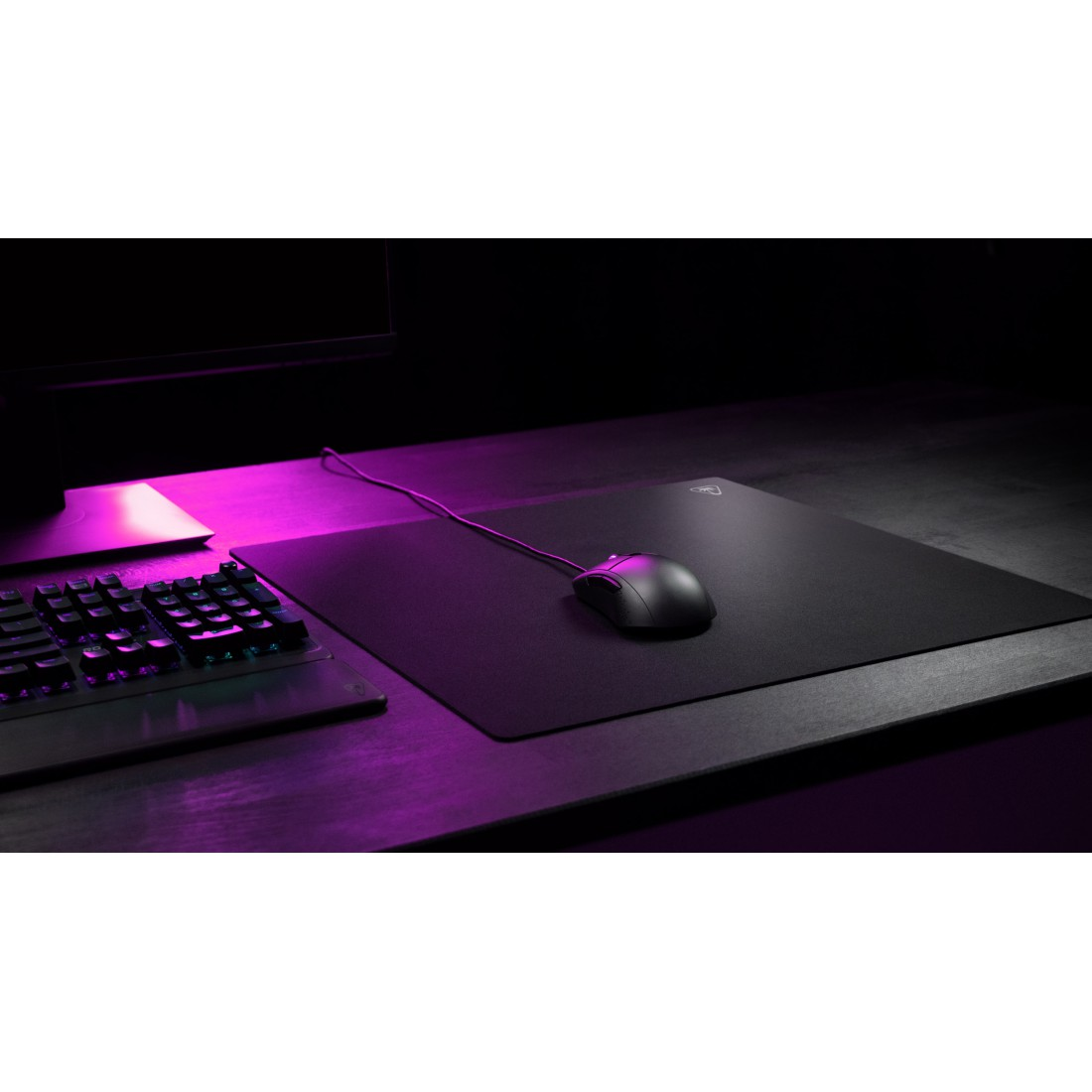 Schwarze Maus auf großem schwarzen Mauspads. Tastatur sichtbar.