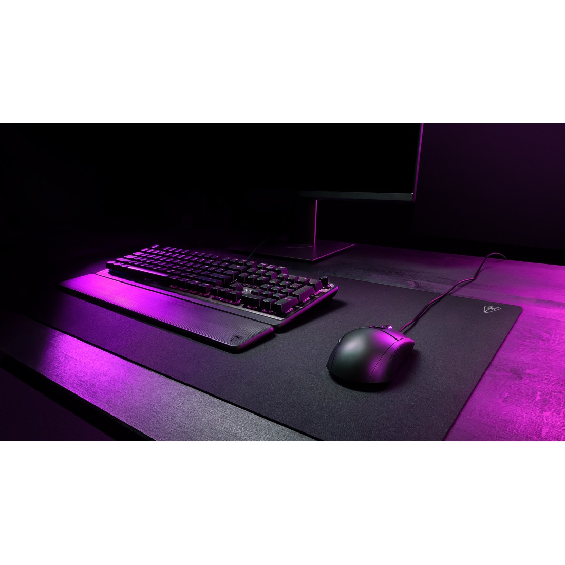 Schwarzes Gaming-Setup mit Tastatur, Maus und Mauspad unter lilafarbenem Licht. Dunkler Hintergrund.