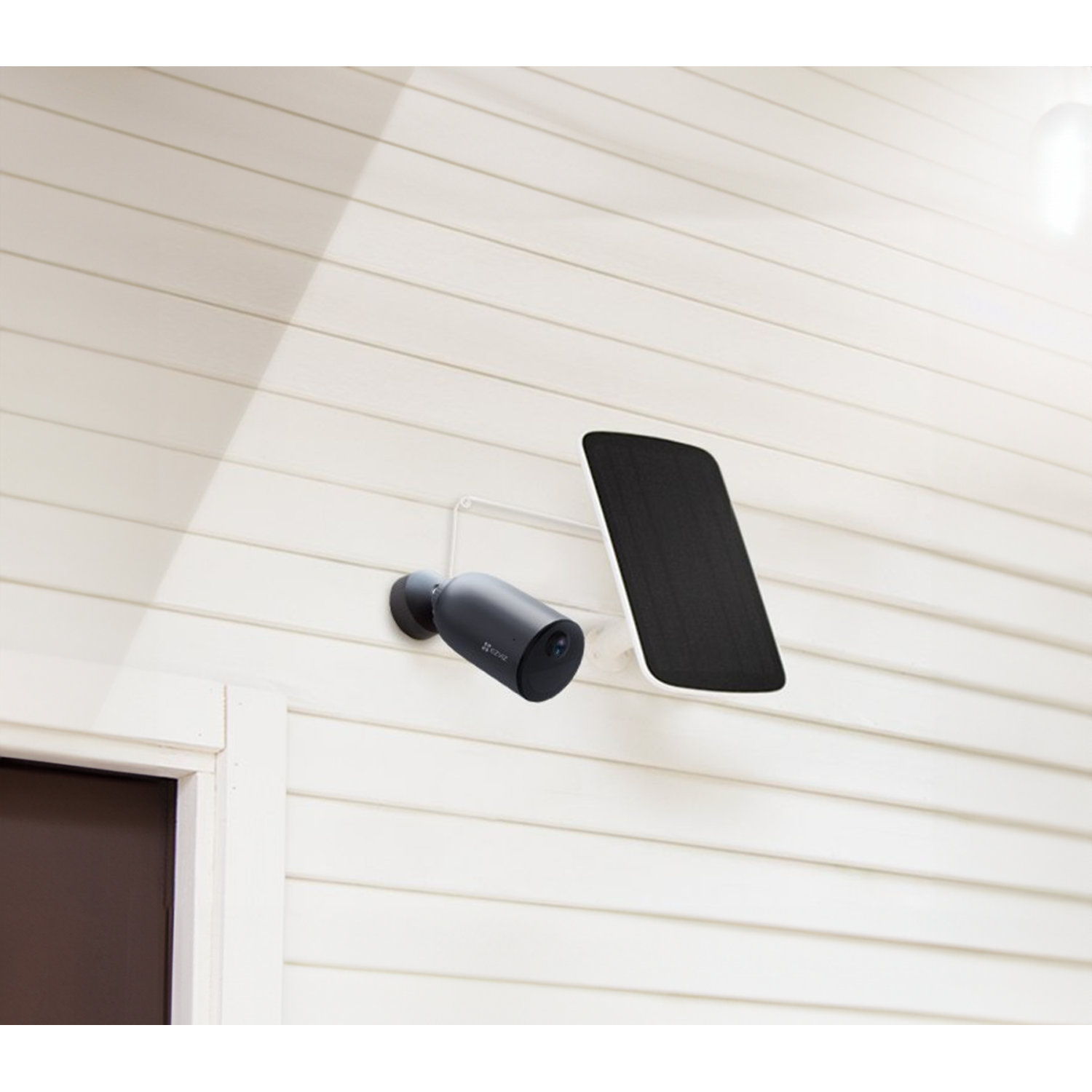 Outdoor security camera on a white house. Solar panel is next to it.