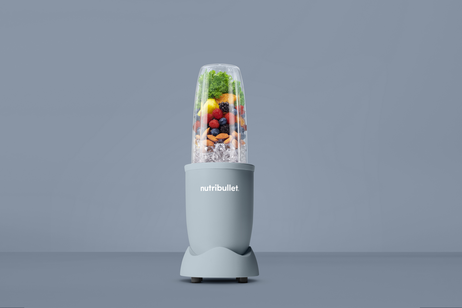 Una licuadora Nutribullet llena de frutas y hielo.