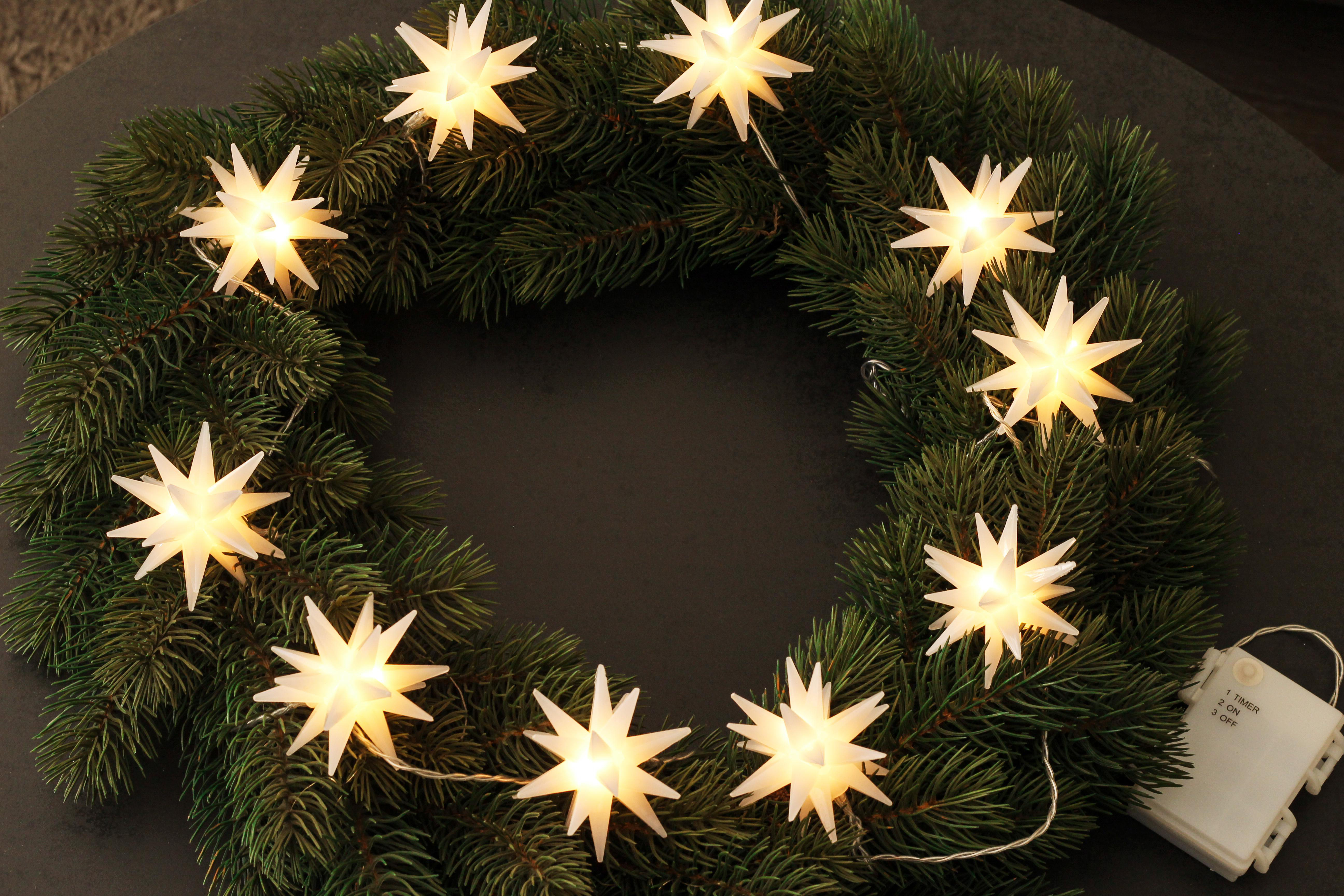 Weihnachtskranz mit sternförmigen Lichtern. Die Lichter sind weiß und hell.