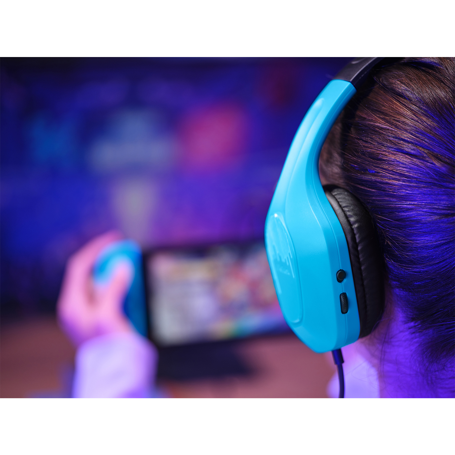 Una persona con cuffie blu gioca su una console portatile.