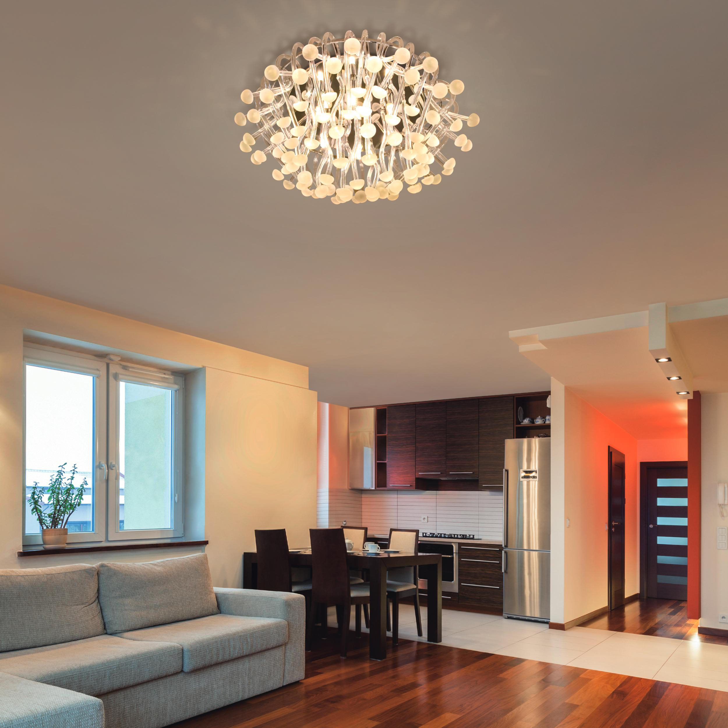 Ein modernes Wohnzimmer mit Holzböden, einem grauen Sofa und einem großen Kronleuchter.
