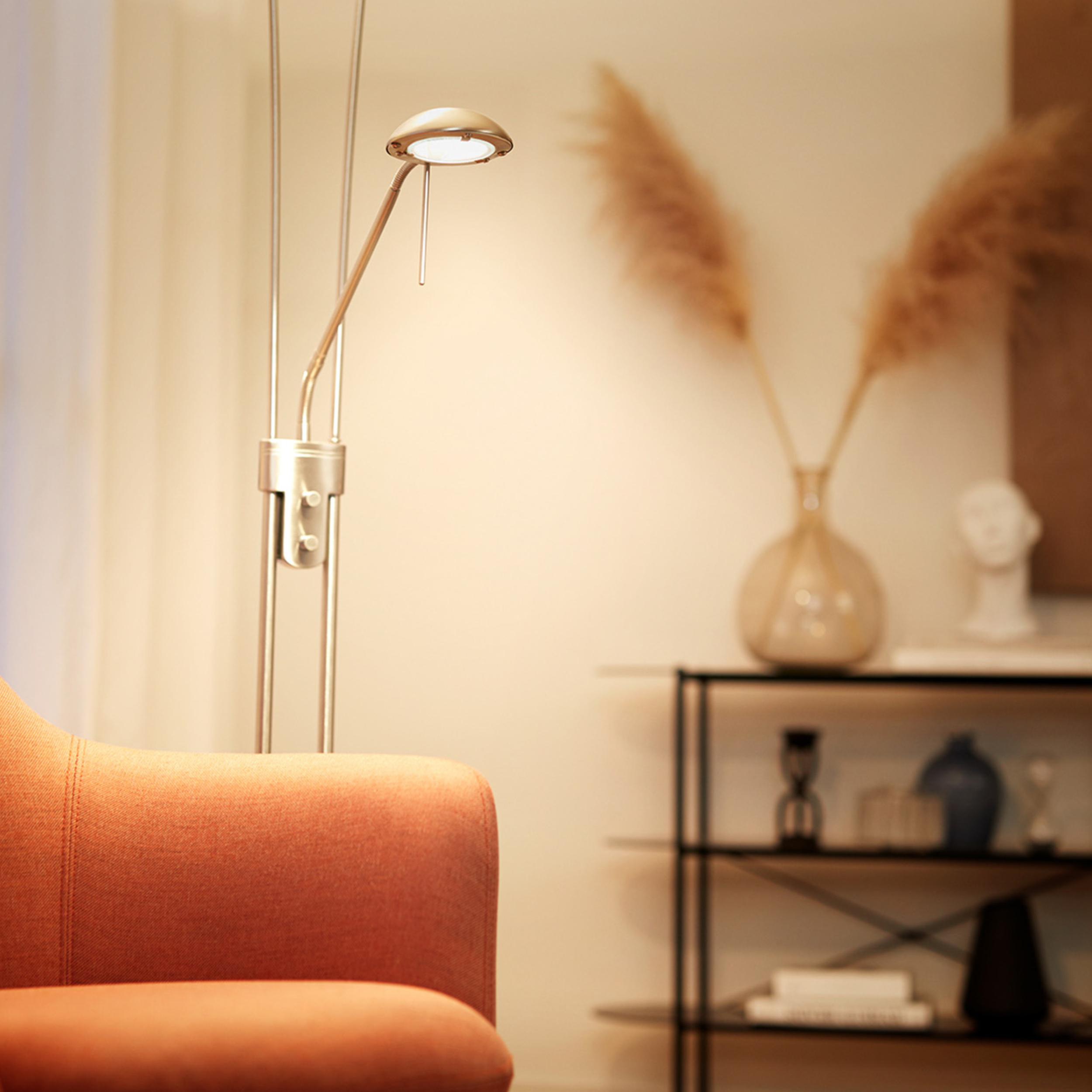 Moderne Stehlampe beleuchtet einen orangefarbenen Sessel und einen Beistelltisch.
