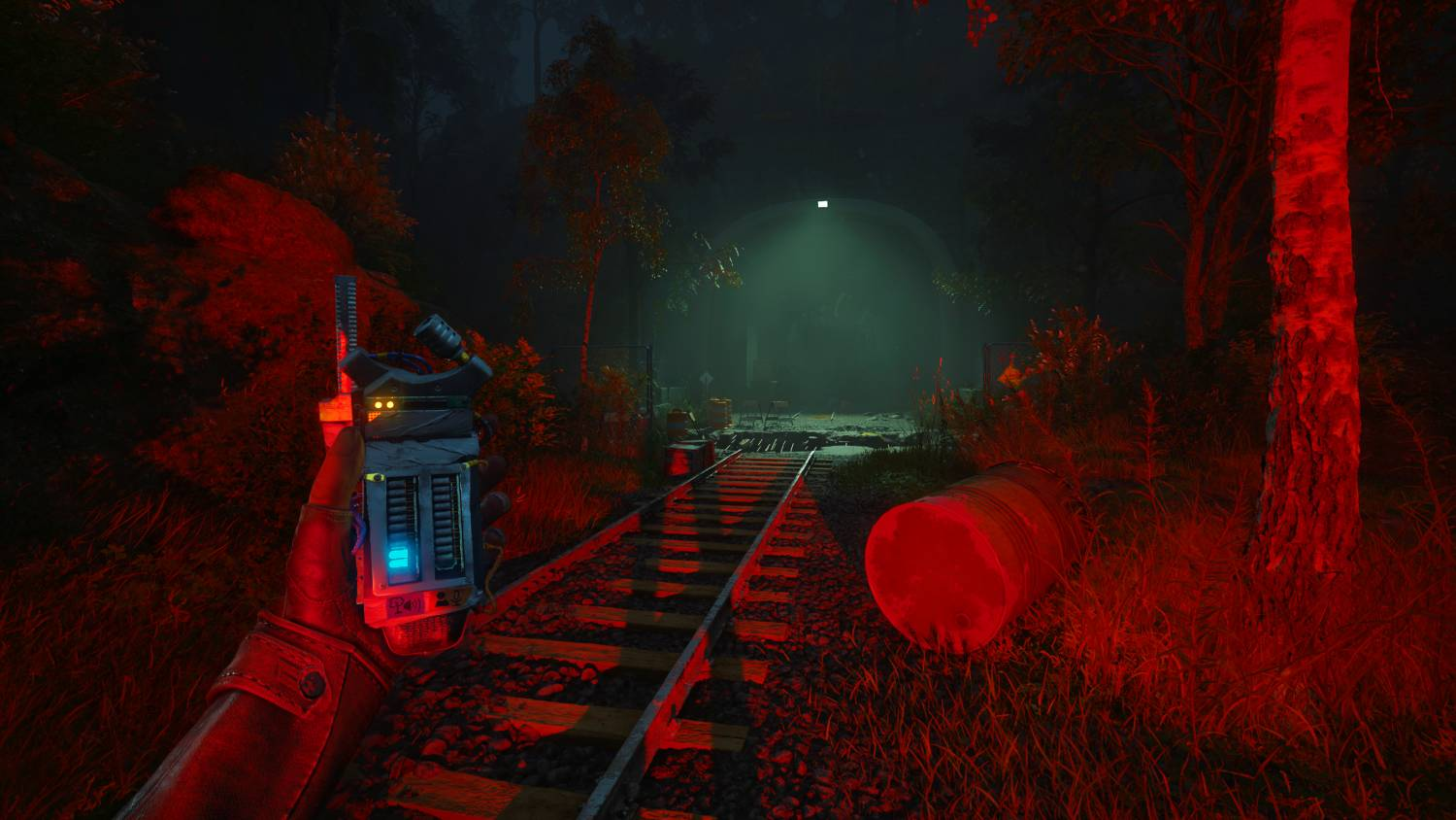 Una persona sostiene un dispositivo, mirando hacia un túnel oscuro con alrededores iluminados en rojo.