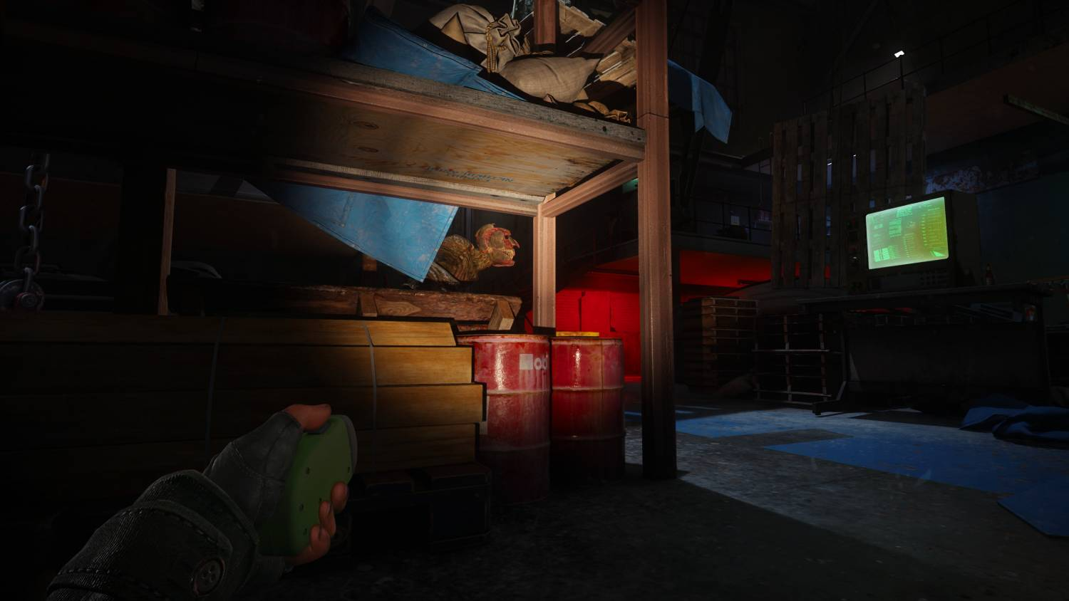 Una habitación oscura y con poca luz con una litera y barriles. Una mano sostiene una linterna.