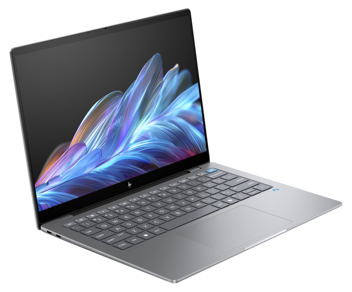 Srebrny laptop z kolorowym wyświetlaczem i jasnoszarą klawiaturą na białej powierzchni.