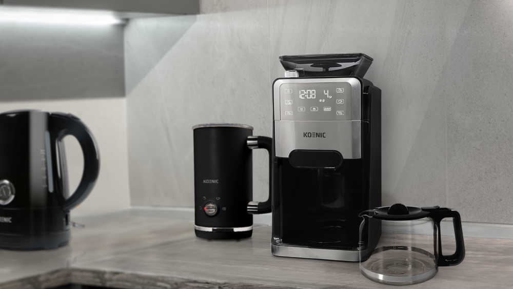 Kitchen setup with a kettle, milk frother, coffee machine, and coffee pot.