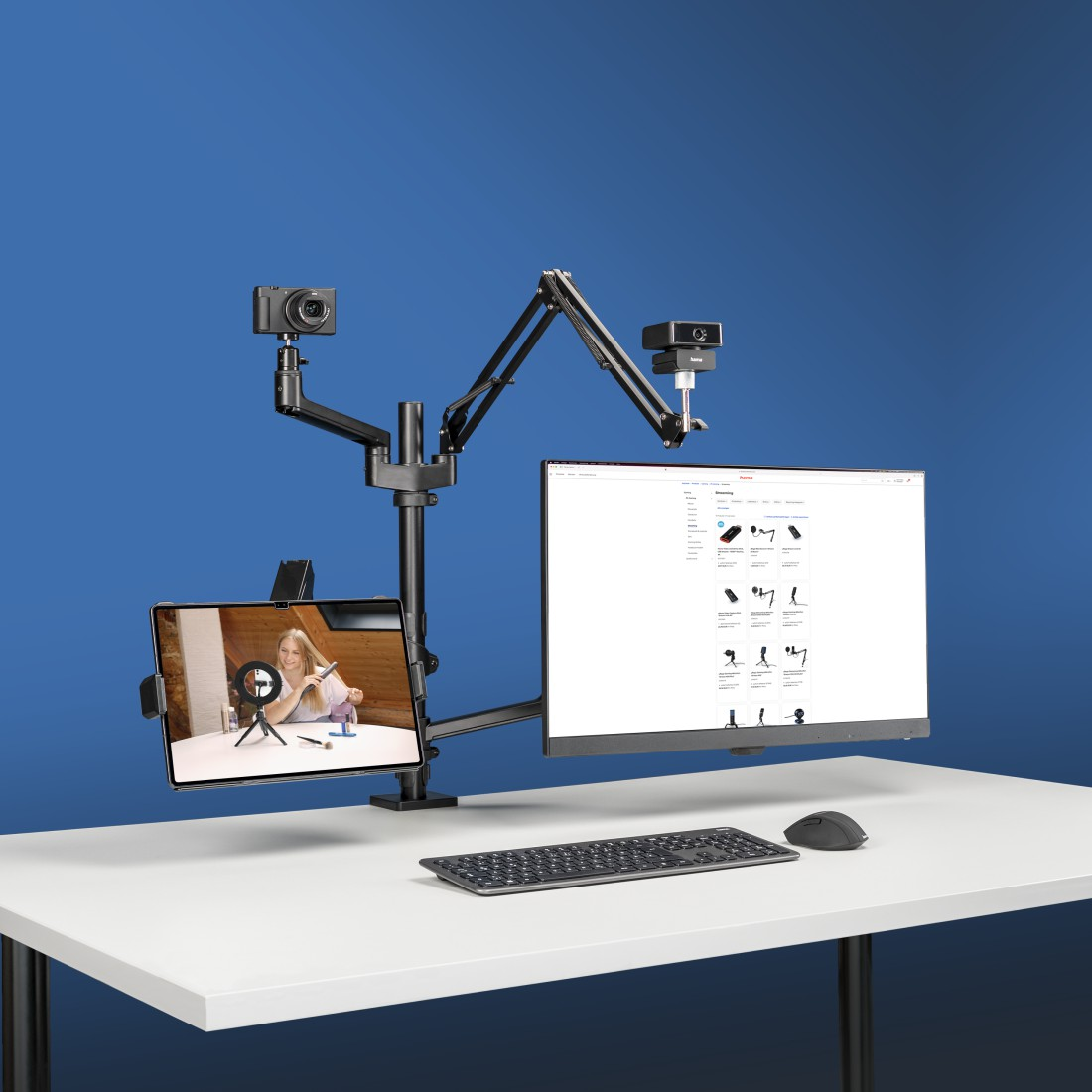 Configuration de bureau avec un moniteur, une tablette, une caméra, un clavier et une personne ajustant l'angle de la caméra.