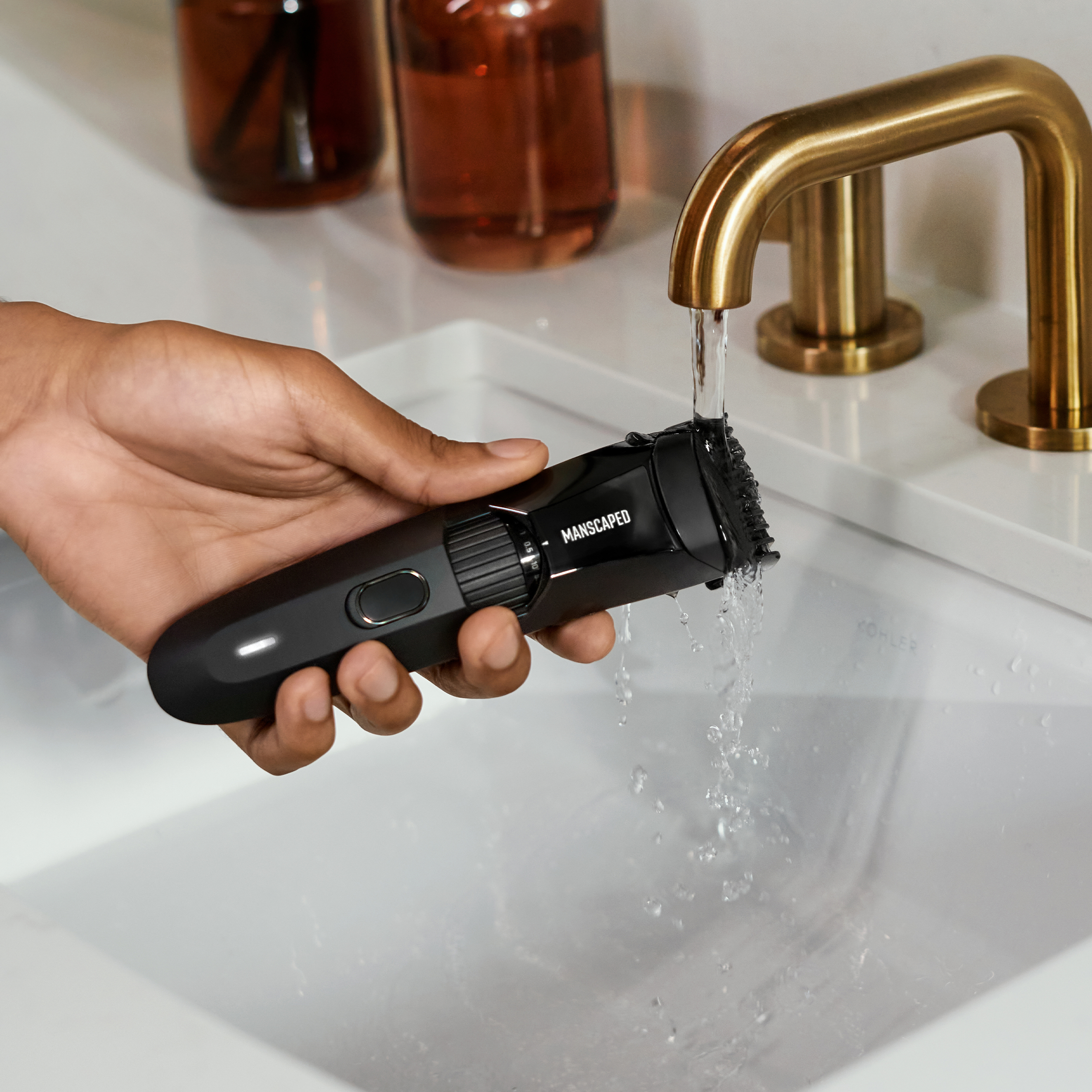 Ein schwarzer Trimmer, der unter fließendem Wasser aus einem goldenen Wasserhahn gereinigt wird.